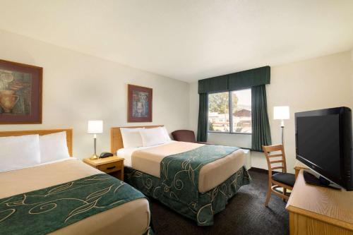 a hotel room with two beds and a flat screen tv at Travelodge by Wyndham Yampa in Yampa