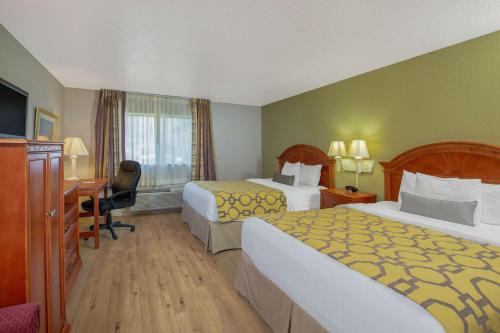 a hotel room with two beds and a desk at Baymont by Wyndham Tehachapi in Tehachapi