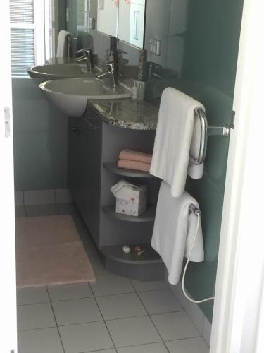 a bathroom with a sink and a mirror and towels at Oneroa Bay Villas in Oneroa