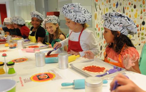 a group of children in chef hats preparing food at The Reef at Atlantis in Nassau