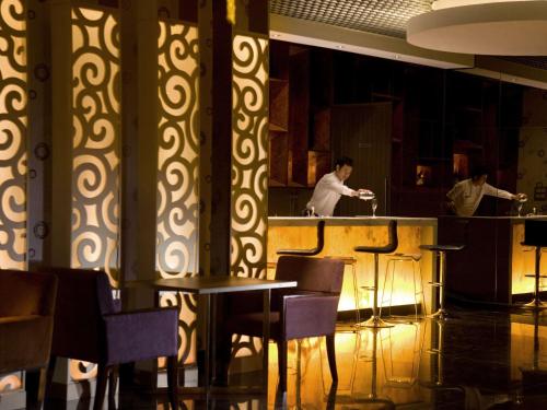 two chefs preparing food at a bar in a restaurant at Novotel Bangka Hotel & Convention Center in Pangkalpinang
