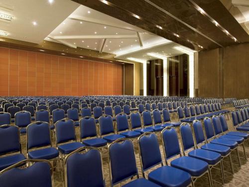 an empty auditorium with blue chairs in a room at Novotel Bangka Hotel & Convention Center in Pangkalpinang