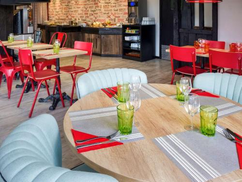 a dining room with wooden tables and red chairs at ibis Styles Chartres Métropole in Chartres