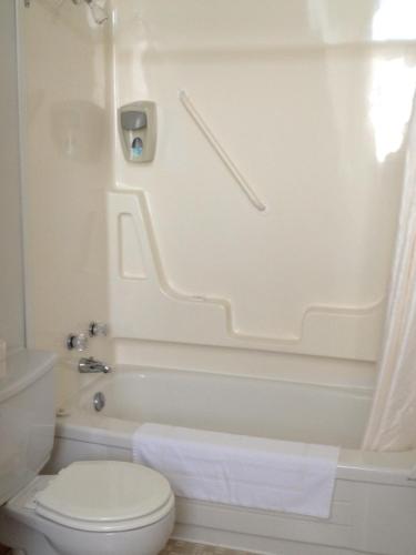 a white bathroom with a toilet and a tub and a toilet at Hopewell Rocks Motel & Country Inn in Hopewell Cape