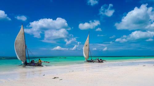 two boats with sails on a beach in the ocean at Villa Lala in Kiwengwa