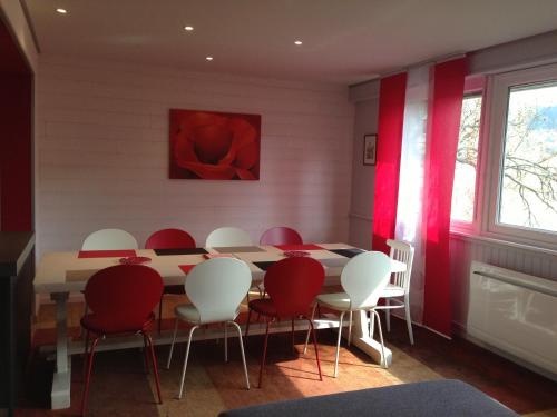 a dining room with a table and red and white chairs at Chalet en Couleurs in Xonrupt-Longemer