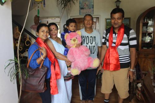 a group of people posing for a picture with a teddy bear at Mansarover Home Stay in Kalimpong