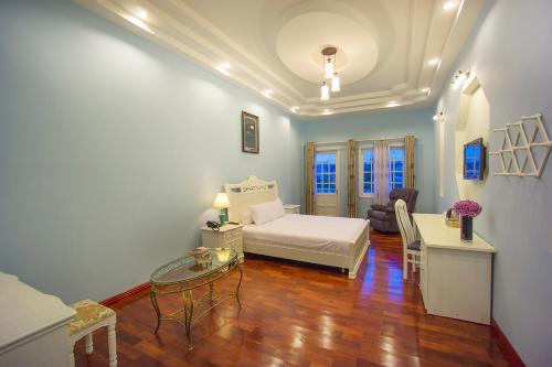 a bedroom with a bed and a table and a couch at Dalat Terrasse Des Roses Villa in Da Lat