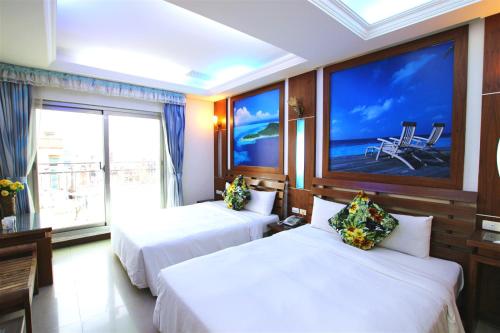 2 camas en una habitación de hotel con una pantalla grande en 墾丁貝殼灣旅店, en Kenting