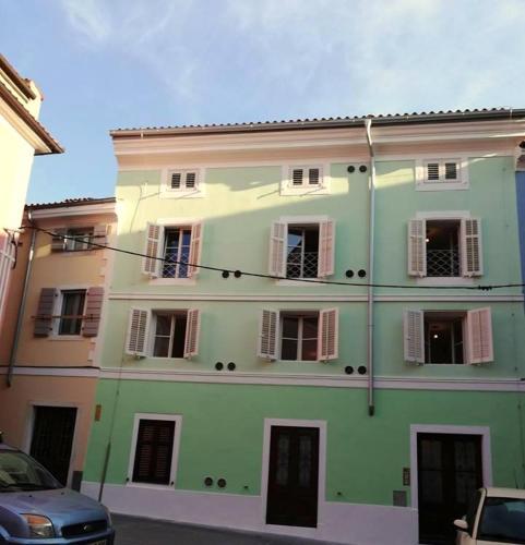 a green building with windows and a car parked in front at Apartment Lunaja in Piran