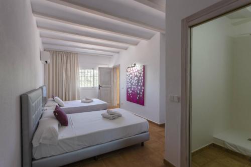 イビサ・タウンにあるVilla Savines is a luxury villa close to Ibiza Town and Playa Den Bossaのベッドルーム1室(ベッド2台付)、スライド式ガラスドアが備わります。