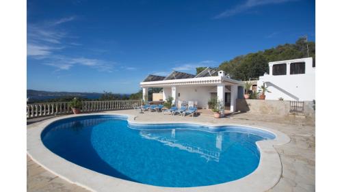 a swimming pool in front of a house at Can Tunicu has amazing sea views and is located in a quiet area near to San Antonio in San Antonio