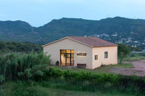 una pequeña casa en un campo con montañas en el fondo en La Frasera Alojamiento Rural, en Vacarisses