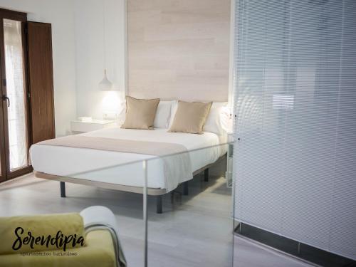 a bedroom with a bed and a glass wall at Serendipia San Justo in Cáceres