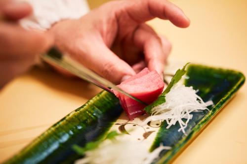 a person cutting up a watermelon with a knife at Novotel Okinawa Naha in Naha