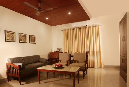 a living room with a couch and chairs and a table at Bhasuri Inn Guruvayoor in Guruvāyūr