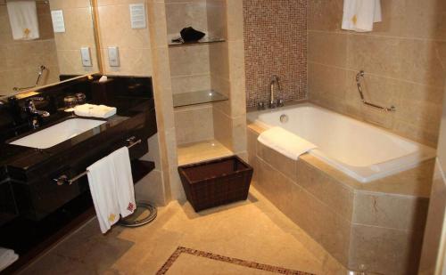 Jinling New Town Hotel Nanjing في نانجينغ: حمام مع حوض كبير ومغسلة