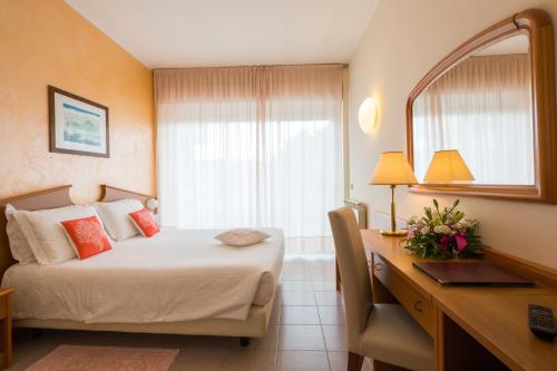 a hotel room with a bed with a desk and a window at Corallo Wellness Hotel in Diano Marina