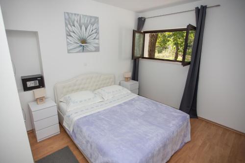 a white bedroom with a bed and a window at Villa Zrinka **** in Svinišće