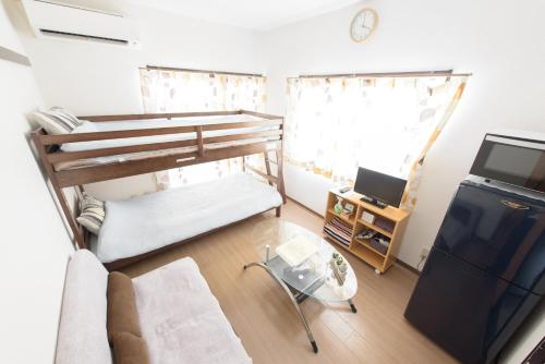 Cette petite chambre comprend des lits superposés et une télévision. dans l'établissement Cocostay Jarudan ココステイ ジャルダン, à Hiroshima