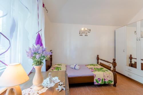 a small bedroom with a bed and a table with flowers at Vila Maslinica in Pučišća