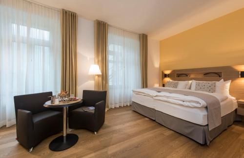 um quarto de hotel com uma cama, uma mesa e cadeiras em Hotel Fravi em Andeer