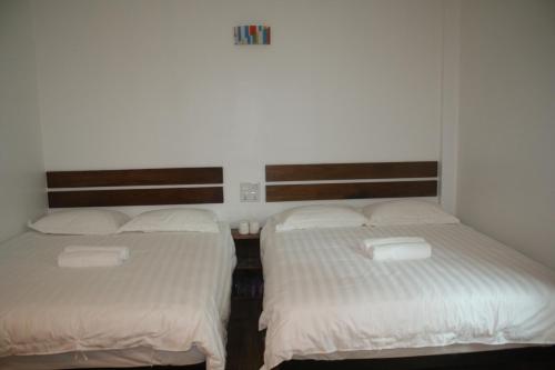 two beds in a room with white sheets at Cozy Riverside Hotel in Melaka