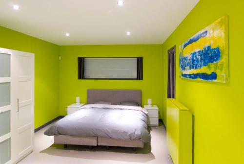 sypialnia z łóżkiem i ścianami w odcieniach limonki w obiekcie WELLNESSLOFT w mieście De Haan