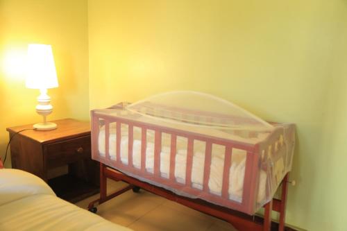 a crib in a bedroom with a lamp and a bed at Engiri Game Lodge and Campsite in Katunguru