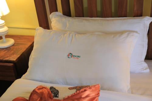 a bed with white pillows with a sticker on it at Engiri Game Lodge and Campsite in Katunguru
