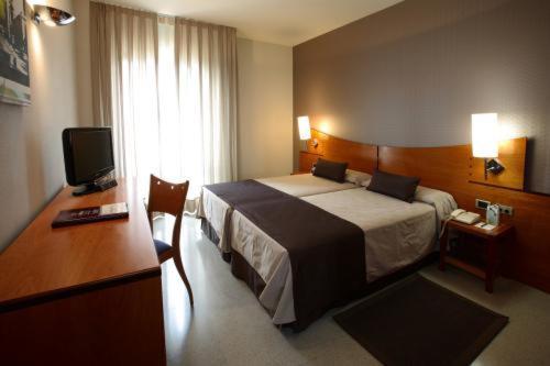 een hotelkamer met een bed, een bureau en een televisie bij Hotel Granollers in Granollers