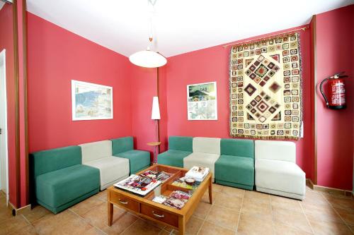 a living room filled with furniture and a red wall at Albergue O Durmiñento in Sarria