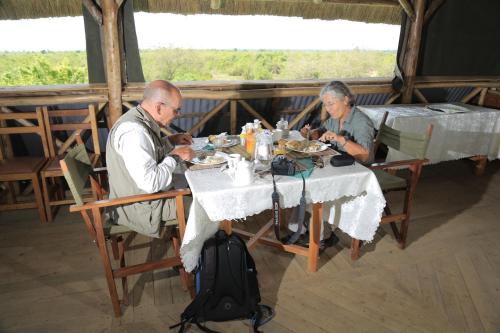 two people sitting at a table eating food at Engiri Game Lodge and Campsite in Katunguru