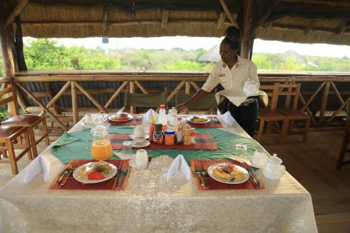 a woman standing in front of a table with food at Engiri Game Lodge and Campsite in Katunguru