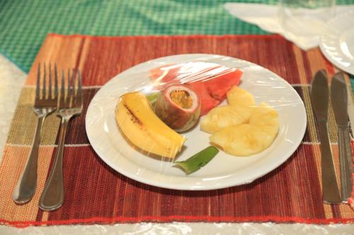 a plate of fruit on a table with forks and knives at Engiri Game Lodge and Campsite in Katunguru