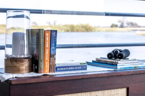 a table topped with books and a glass at The Namushasha River Villa in Kongola