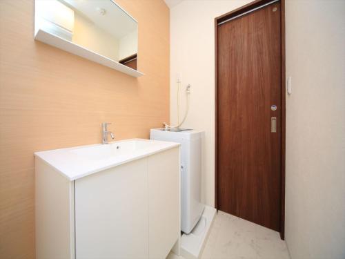 a bathroom with a sink and a toilet and a wooden door at COTO Tokyo Shibuya 4 in Tokyo
