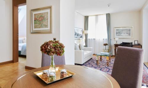a living room with a table with a vase of flowers at Living Hotel De Medici in Düsseldorf