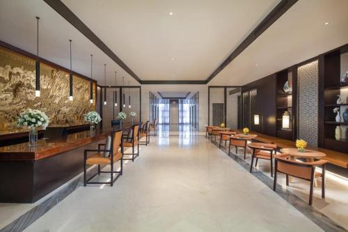 a restaurant with a long line of tables and chairs at Ramada by Wyndham Taizhou in Tiantai