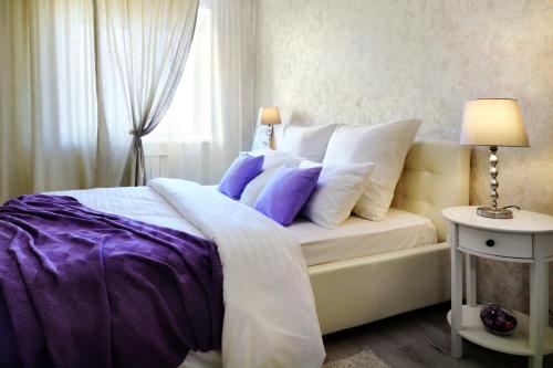 a bedroom with a bed with purple and white pillows at PaulMarie Apartments on Chigrinova in Mogilev