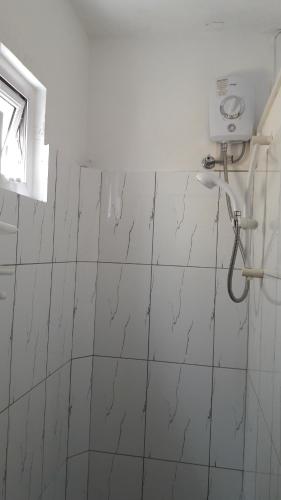 a bathroom with a white tiled wall with a shower at Villas Floralies in Grand-Baie