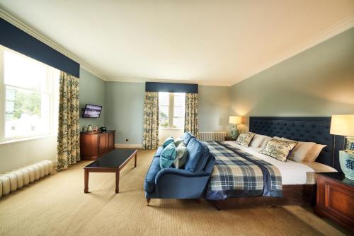 1 dormitorio con 1 cama y 1 silla azul en Golf View Hotel & Spa, en Nairn