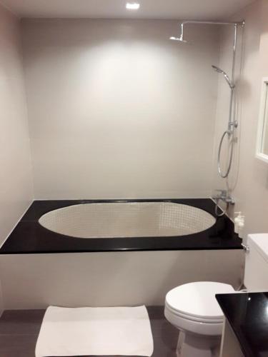 a bathroom with a bath tub with a toilet at Paragon Inn in Lat Krabang