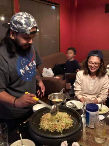 a man preparing food in a pan on a table at HappyCloset&WasamonHostel in Kumamoto