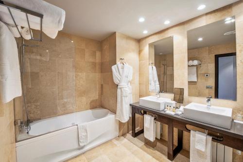 a bathroom with two sinks and a bath tub and a tubermott at Hotel La Caminera Club de Campo in Torrenueva