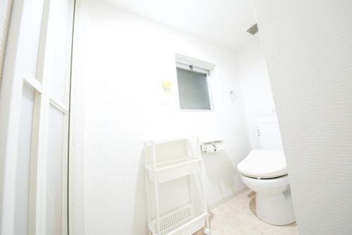 ein weißes Bad mit einem WC und einem Spiegel in der Unterkunft Guest House Re-worth Yabacho1 301 in Nagoya