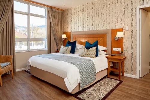 Habitación de hotel con cama grande con almohadas azules en First Group Mount Sierra, en Ciudad del Cabo