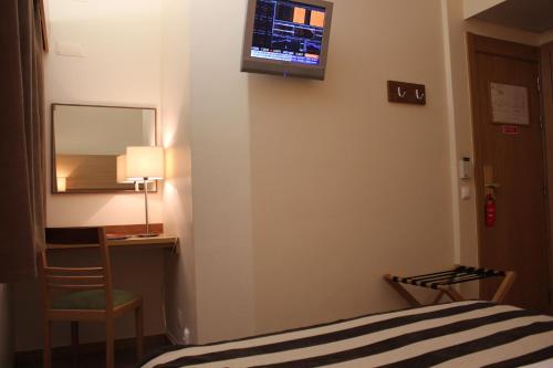 a hotel room with a bed and a desk and a mirror at Hotel Principe Lisboa in Lisbon