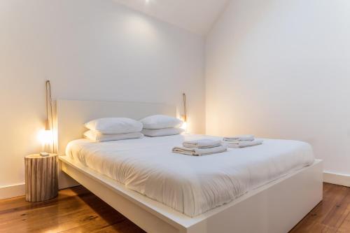 a white bed with white pillows and towels on it at LX 77 in Lisbon