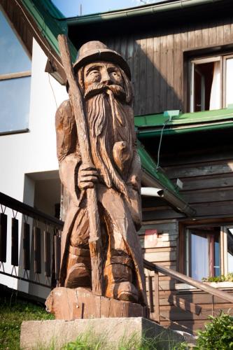 a wooden statue of a man holding a stick at Penzion Pohlednička in Benecko